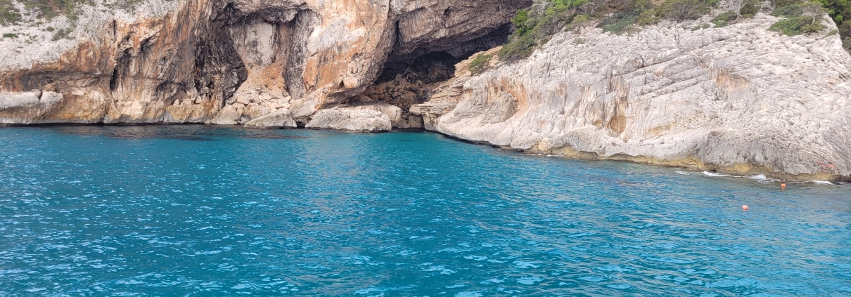 Türkisfarbenes Meer vor steiler Felsküste mit Höhle an der Ostküste Sardiniens