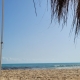 Sandstrand von Hammamet in Tunesien mit reetgedecktem Sonnenschirm und Liegestuhl am Meer